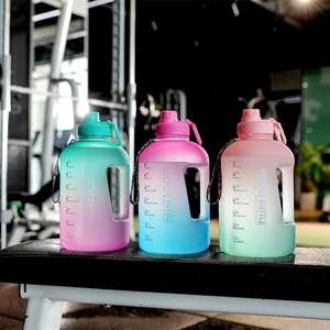 Three gradient large capacity sports water bottles with time markers on a gym bench
