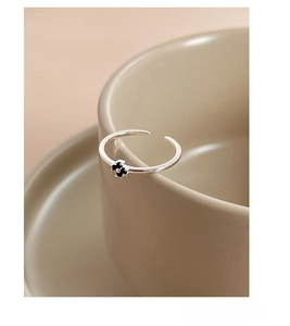 Detail of adjustable S925 sterling silver ring with black clover on a ceramic cup