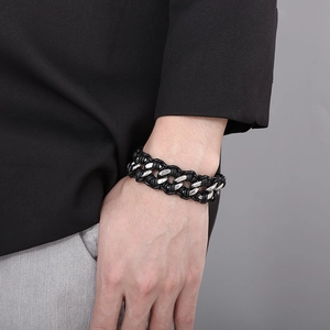 Macro shot of a men's black braided leather bracelet with integrated steel chain detail