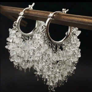 Elegant silver hoop earrings with cascading crystal tassels on a dark background