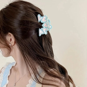 Light blue heart hair claw clip with pink checkered pattern shown on a messy bun hairstyle