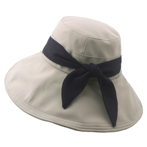 Dettaglio cappello da sole beige a tesa larga con fiocco blu scuro in tessuto pregiato