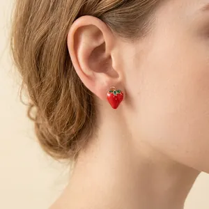 Sparkly strawberry stud earring with red enamel and gold stem shown on a female model