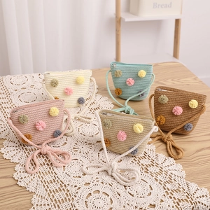 Detailed view of handmade straw crossbody bags with colorful plush balls in five colors