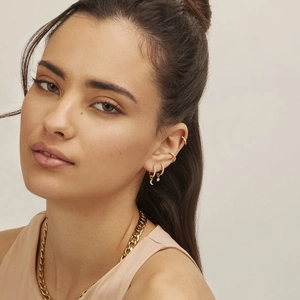 Close-up of gold star and moon drop earrings with cuban chain necklace on model