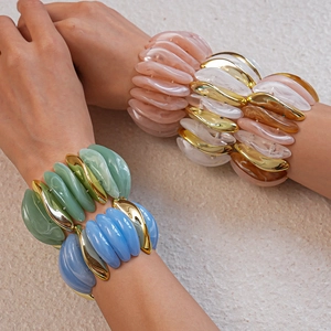 Close-up of stacked acrylic stretch bracelets with marbled patterns and gold metal accents