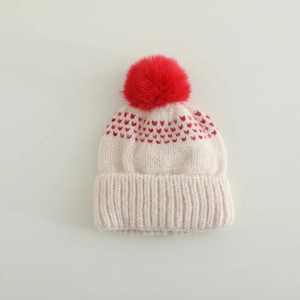 Détail du bonnet en tricot avec motifs de cœurs rouges, bord côtelé et pompon