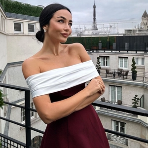 Detail of elegant off-shoulder contrast dress in burgundy red with Paris city view