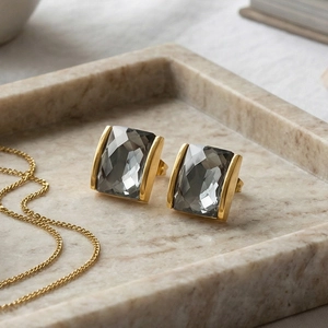 Macro detail of rectangle gray crystal earrings with 18K gold plated base on marble tray