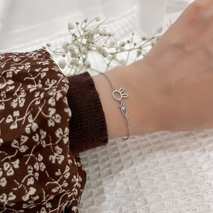 Close-up of silver rabbit and carrot charm bracelet with small diamond on a female wrist
