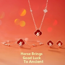 Detailed close-up of red clover jewelry set with gold horse emblem and crystal accents
