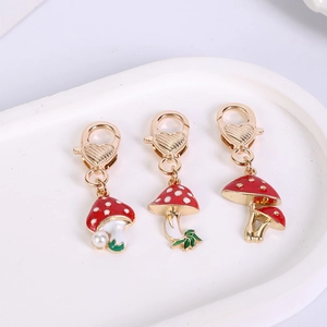 Detail of red mushroom charms with gold lobster clasps and delicate pearl accents