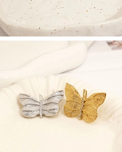 Macro shot of silver and gold butterfly brooches with brushed metal and crystals