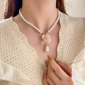 Close-up of French floral pearl necklace with bow detail and teardrop pendant on model