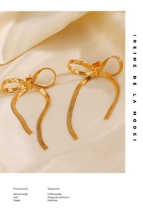 Détail de boucles d'oreilles nœud en or 18K avec pampilles sur fond en satin