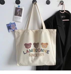 Detail view of cream canvas tote bag with three embroidered bears and aesthetic hanging decor