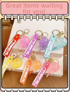 Close-up of colorful resin lollipop keychains with glitter, golden bells and silicone straps