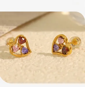 Close-up of heart-shaped gold earrings featuring three-color inlaid cubic zirconia stones