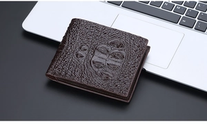 Close-up of dark brown crocodile texture men wallet on silver laptop touchpad