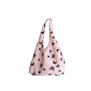 Pink canvas tote bag featuring black butterfly prints and integrated shoulder handles