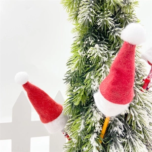 Close-up of mini red felt Santa hats for lollipop decoration on a snowy Christmas tree