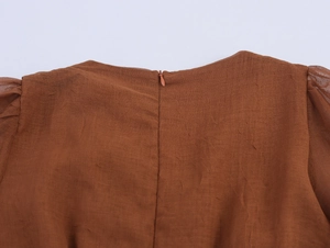 Detail of the caramel textured fabric dress showing the invisible back zipper and neckline