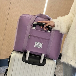 Large purple waterproof nylon travel bag with trolley sleeve on white suitcase