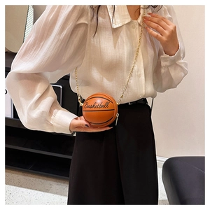Detail view of the orange basketball-shaped mini bag with chain strap and printed text