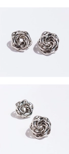 Close-up of artistic silver spiral rose earrings with irregular metallic flower design