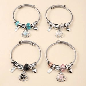 Flat lay of four beaded bangle bracelets with colorful crystal charms and heart tags