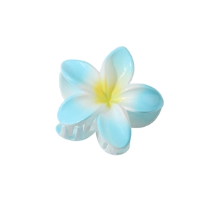 Détail de la pince à cheveux fleur de frangipanier en dégradé bleu et blanc avec centre jaune