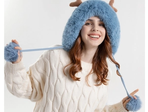 Detail view of blue knit hat with antlers and plush pom-pom drawstrings