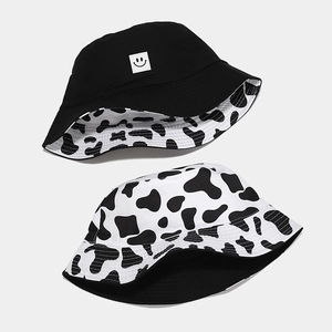Reversible bucket hat with smiley face patch and black and white cow print patterns