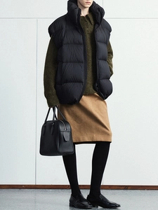 Close-up of olive green knit sweater paired with a black standing collar down vest