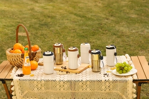 Portable 316 stainless steel coffee mugs displayed on a camping table in a nature setting