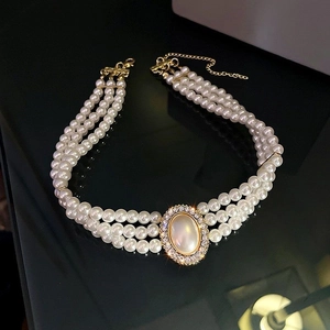 Macro detail of triple-layer pearl choker with oval cat-eye stone and lobster clasp