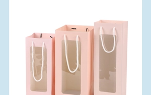 Detailed view of pink paper gift bags featuring a large rectangular clear PVC window