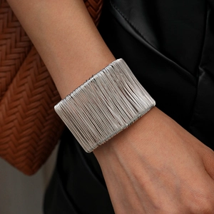 Close-up of a silver multi-layer wire wrapped cuff bracelet worn by a model