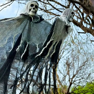 Scary Halloween hanging ghosts with skull heads and black tattered fabric on tree branches
