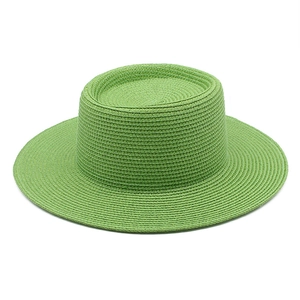 Detail view of the flat-top grass green straw hat with woven texture and wide brim