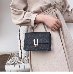 Detail of a black geometric crossbody bag with a gold U-shaped clasp and metal chain strap