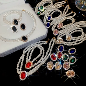 Macro detail of multi-layer pearl jewelry set with sparkling oval gemstone pendants
