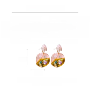 Detail view of flower and butterfly drop earrings with size markers in centimeters