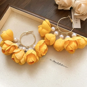 Detail of yellow fabric flower earrings with white pearls and large golden hoops