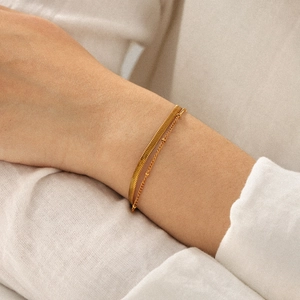 Close-up of double-layer 18k gold plated flat snake chain and beaded bracelet on wrist