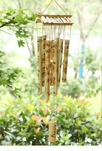 Detail of handcrafted bamboo wind chime with burnt spiral patterns against natural green background