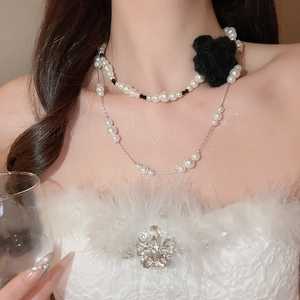 Close-up of double-layer pearl necklace with a black knit flower on a model