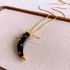 Macro detail of horn pendant with golden dots and polished link chain necklace