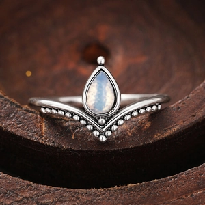 Anello bohémien a V con pietra di luna a goccia su uno sfondo di legno rustico