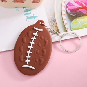 Detailed view of a brown American football keychain with realistic stitching on a pink background
